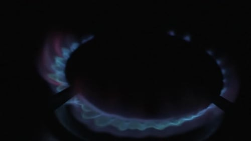 Ein Gaskocher, der im Dunkeln aufleuchtet und einen blauen und roten Flammenkreis bildet.