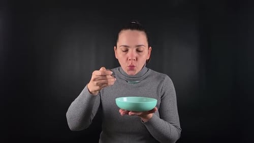 Woman Eats Soup From Bowl With Spoon