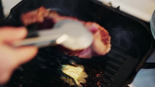 Nahaufnahme eines saftigen Steaks, das mit einem Spatel auf einer heißen Grillpfanne gedreht wird