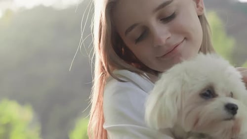 Smiling Woman Holding a White Dog Outdoors
