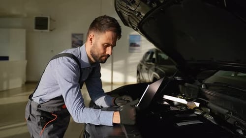 Automechaniker analysiert die Diagnose von Automotoren auf einem Laptop