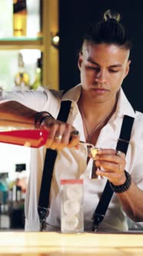 Bartender Pours Drink Through Jigger in Bar Setting