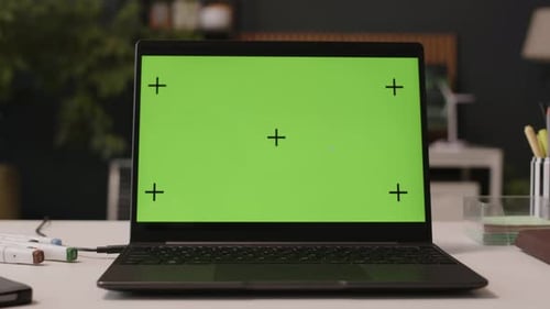 Laptop with Green Template Screen on Desk in Green Office