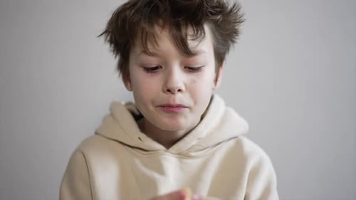 Teenager of thirteen years eating tangerine. The boy takes a piece by piece chewing a fruit.