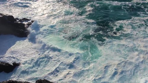 Swirling Sea Waves Crashing On The Rocks With White Foam During Sunrise. Slow Motion