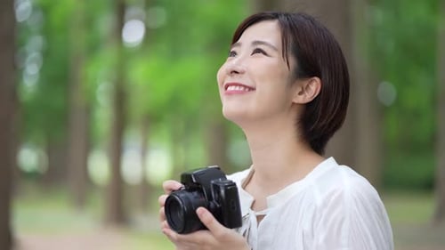 Smiling Woman with Camera in Leafy Green Park