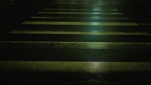 Uma faixa de pedestres mal iluminada na superfície da estrada de asfalto à noite