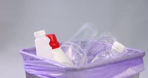 Hand putting plastic waste into recycling bin