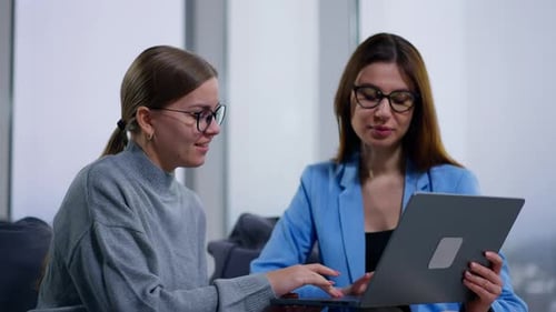 Two Women Collaborating on Laptop in Office