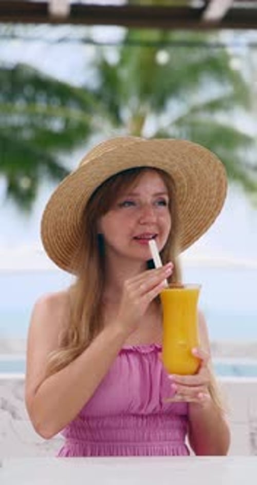 Woman Enjoying Tropical Cocktail on Beach Vacation Wearing Straw Hat