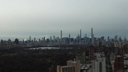 A high angle, aerial view of Central Park in New York City on a cloudy morning. The drone camera tru