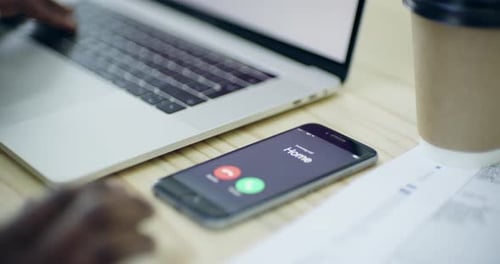 Typing on laptop with incoming call on phone