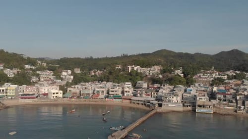 Aerial approach into a coastal village located in a beautiful ocean bay.