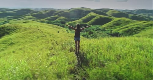 Young Woman Enjoying Freedom in Beautiful Green Hills Landscape