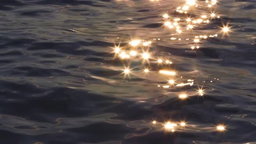 Raios de sol dourados brilham nas ondas da água. O brilho quente reflete no oceano.
