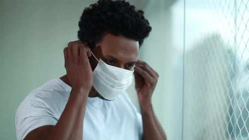 Young Man Puts On Protective Medical Face Mask