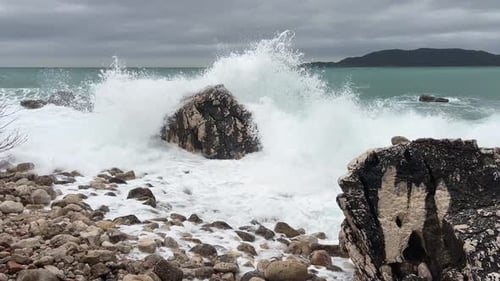 A Large Sea Wave Breaks Against a Rock Standing in the Sea and Splashes Fly Upward