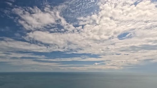 Zeitraffer, flauschige Cumuluswolken, die sich am blauen Sommerhimmel über ruhiger See bewegen, abstrakte Luftbilder, Natur