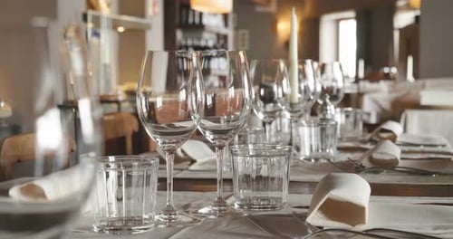 A waiter sets the table in a restaurant before customers arrive, and uses fine cutlery and glasses