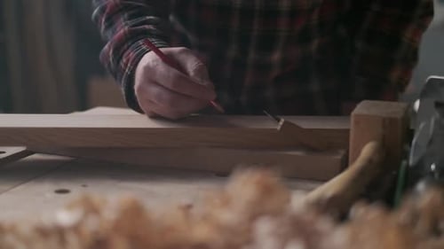 Schreiner misst und markiert Holz in einer stimmungsvollen Werkstatt