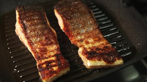 Salmon steaks getting seared on a griddle close up