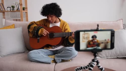 Young Adult Plays Guitar, Sings on Smartphone