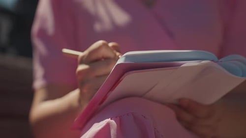 Woman Writes in Notebook in City Park