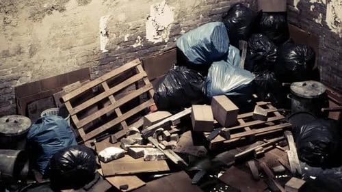 Overflowing Trash in an Abandoned Space with Scattered Debris and Pallets
