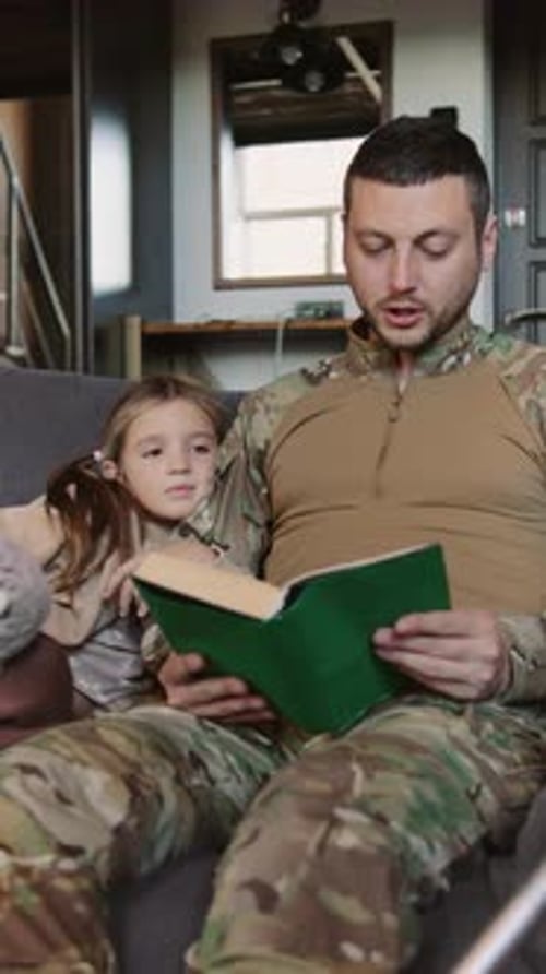 Father Reading Book with Daughter on Living Room Couch
