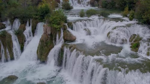 Close up shot of Krka Waterfalls with green foliage and turquoise water, aerial