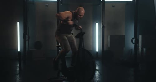 Muscular Man Exercising on Stationary Bike in Gym