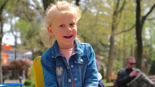 Blonde little girl using the rocking chair at the playground