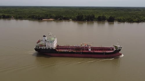 Aerial view of industrial ship transporting oil on Amazon River with green scenery in background