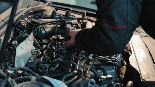 Mécanicien de moteurs en train de régler un technicien spécialisé dans les pièces automobiles au travail Un mécanicien de moteurs qualifié règle un