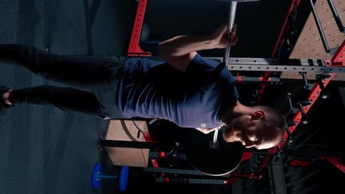 vertical video young motivated bodybuilder squatting with heavy barbell in gym exercise active