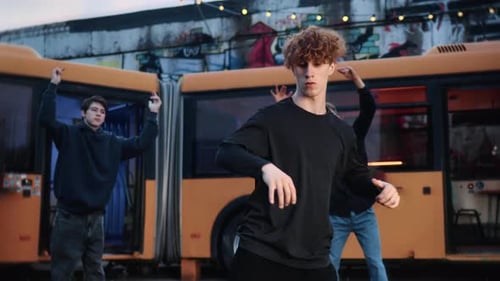 Male Dancers Performing Contemporary Choreography Beside Parked Bus Expressing Urban Street Dance