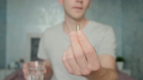 Young Adult Taking Pill With Water