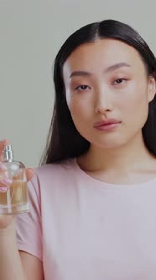 Beautiful Woman Posing with Perfume Bottle in Studio
