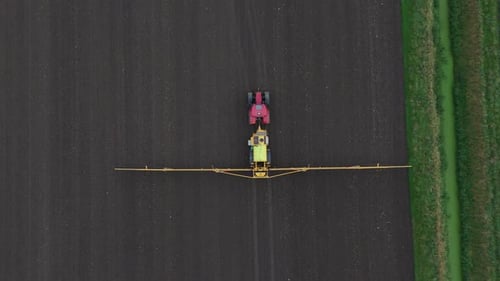 Tractor Spraying Pesticides On agricultural field With Sprayer, topdown aerial