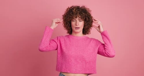 Woman touching head against pink background