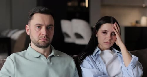 Familia triste sentada en el sofá de la sala de estar Marido y esposa serios viendo la televisión juntos en el sofá