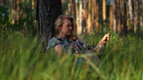 Peaceful girl sits resting and relaxing sitting on the grass in a park, concept of relaxation