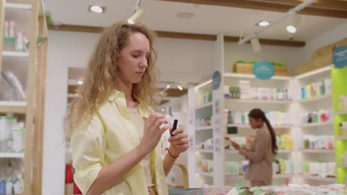 Female Client Choosing Lipstick during Shopping in Cosmetics Store