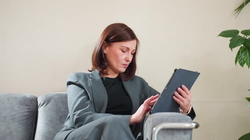 Focused Businesswoman Using Tablet in Office Workspace
