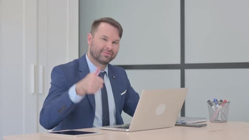 Man in Suit Gives Thumbs Up at Desk