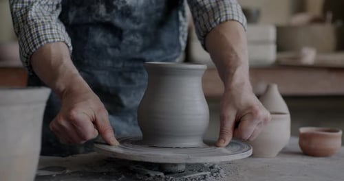 Gros plan d'un potier âgé qualifié fabriquant un pot en céramique sur une roue tournante sur le lieu de travail