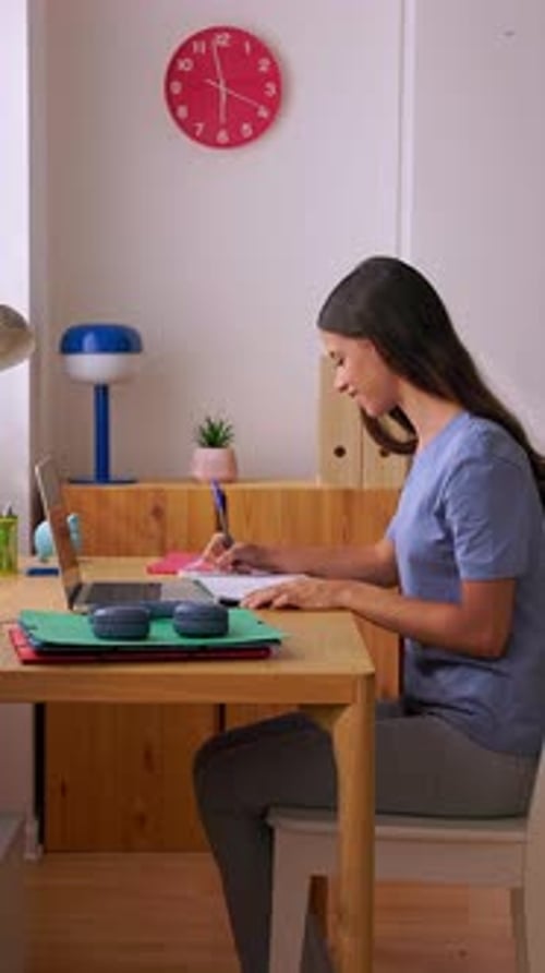 Young Woman Studying at Desk with Laptop and Notebook