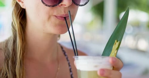 Woman Enjoying Tropical Drink with Sunglasses