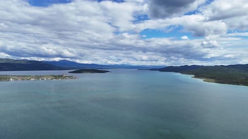 An aerial view captures a vast, tranquil lake stretching towards distant, hazy mountains under a