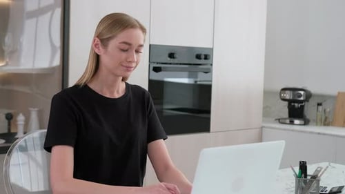 Woman Working On Laptop in Modern Kitchen